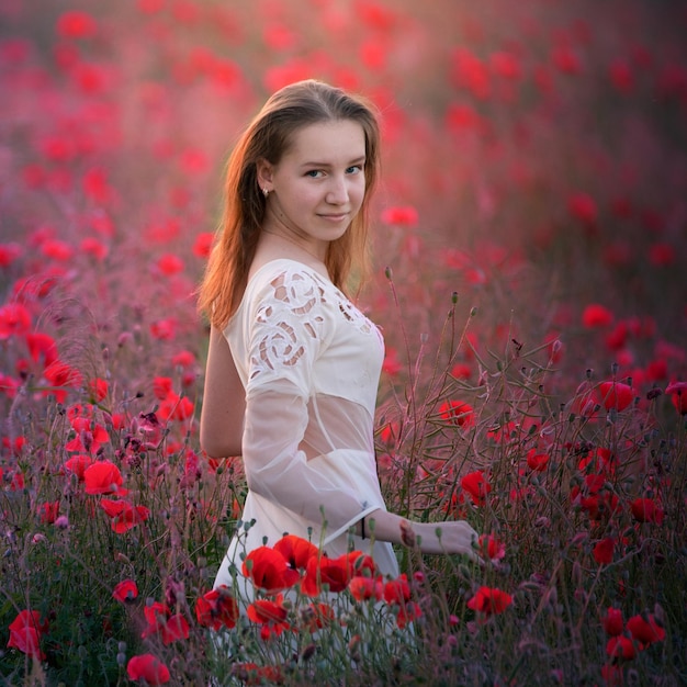 Jong aantrekkelijk meisje in een witte jurk op een veld met tulpen.