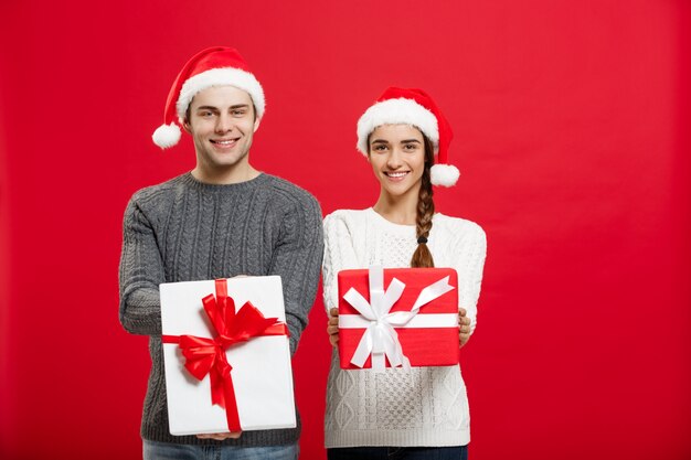 Jong aantrekkelijk paar die giften geven aan elkaar het vieren in Kerstmisdag.