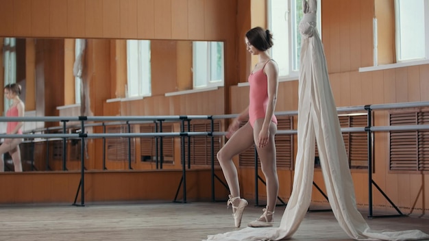 Foto jong acrobatisch meisje toont de flexibiliteit van het lichaam aan de balletbar, circusartiest