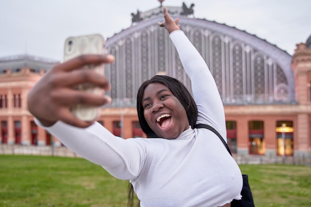 Jong Afrikaans-Amerikaans meisje dat een selfie neemt voor het station van Atocha in Madrid