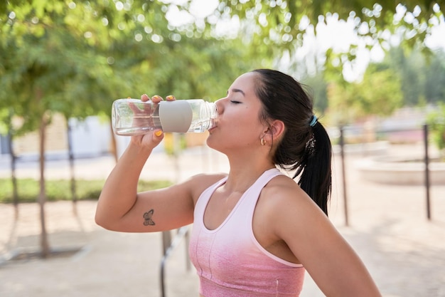 Jong atleet drinkwater na training buitenshuis