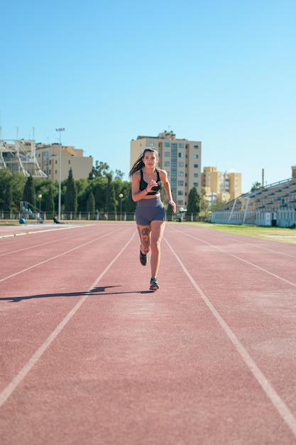 Jong atletisch meisje met tatoeages rent rond een atletiekbaan