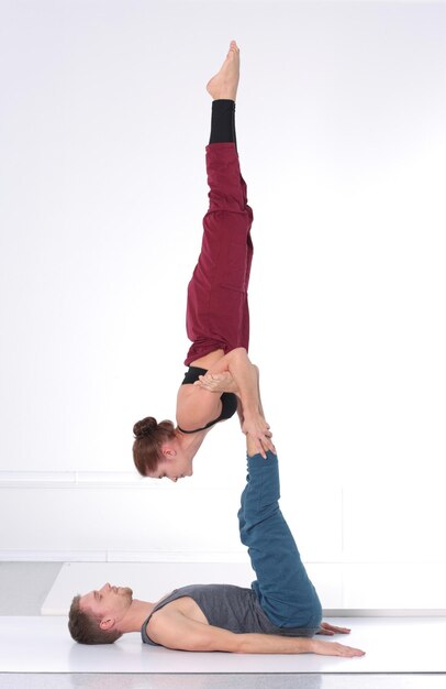 Jong atletisch paar dat acroyoga beoefent. Balanceren in paar.