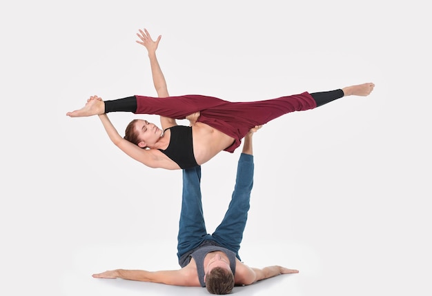 Jong atletisch paar dat acroyoga beoefent. Balanceren in paar.