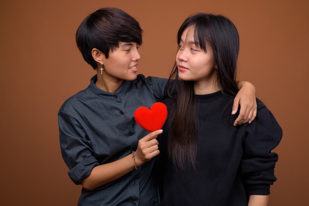 Jong Aziatisch lesbisch paar samen en verliefd tegen bruin