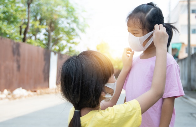 Jong aziatisch meisje dat masker voor zuster draagt om covid 19, het thaise stofmasker van de jong geitjeslijtage te beschermen. bescherm pm 2.5 en stop het coronavirusconcept