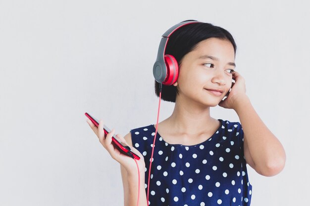 Jong Aziatisch meisje luistert naar muziek van oortelefoons op wit.