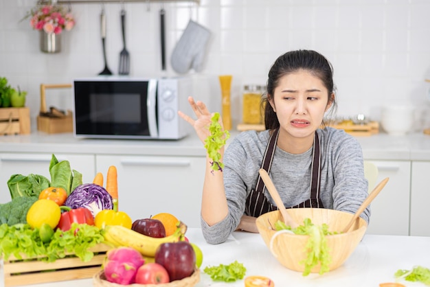 Jong Aziatisch meisje met saai gezicht omdat ze haar gewicht moet verminderen door groene salade en fruit te eten