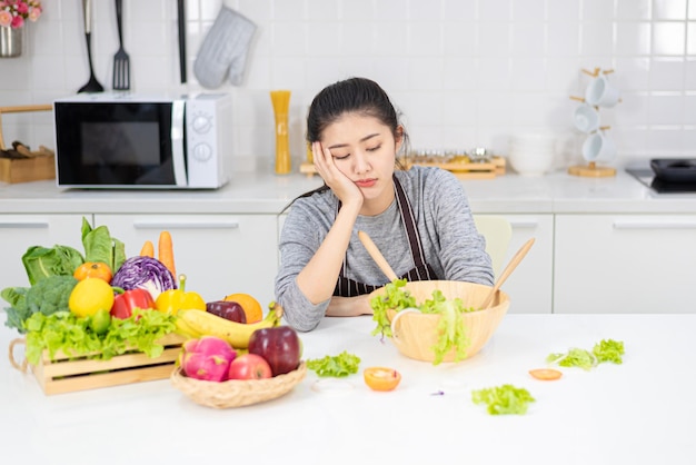 Jong Aziatisch meisje met saai gezicht omdat ze moet afvallen door groene salade en fruit te eten