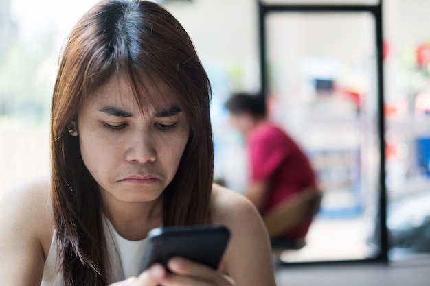 Jong Aziatisch Onderneemstergevoel verveeld tijdens het gebruiken van smartphone op kantoor.