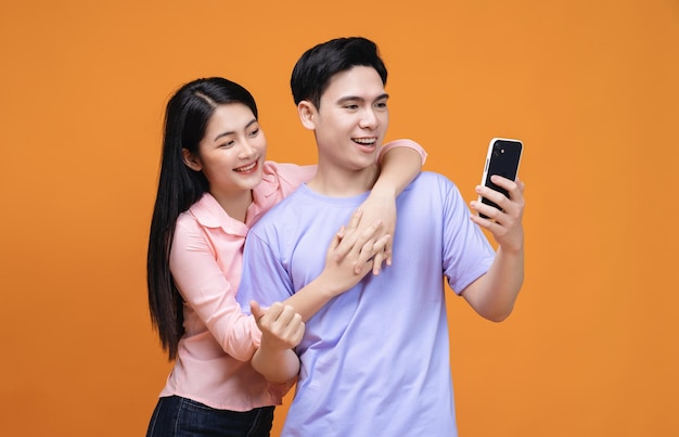 Jong Aziatisch paar dat smartphone op achtergrond gebruikt