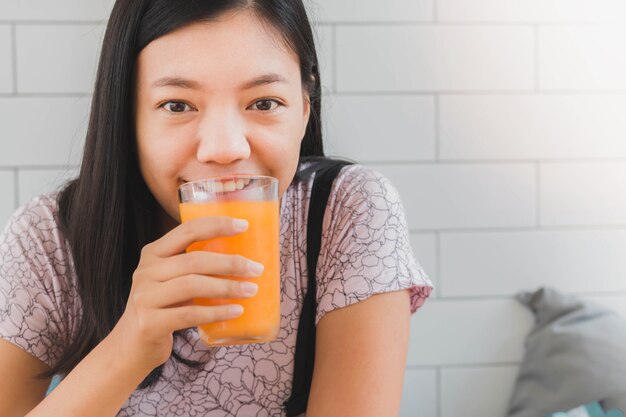 Jong Aziatisch vrouw het drinken Jus d orange thuis