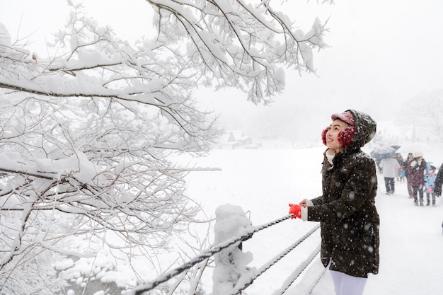 Jong Aziatisch vrouwenmeisje in het seizoen van de de wintersneeuw