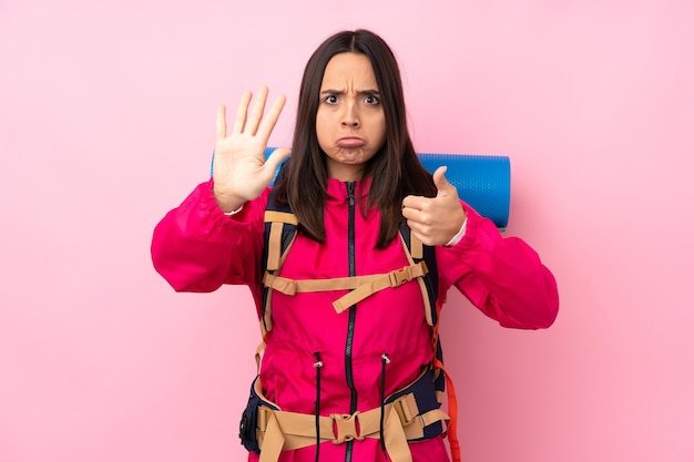 Foto jong bergbeklimmermeisje met een grote rugzak over roze die zes met vingers tellen