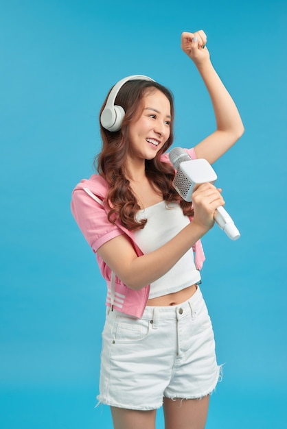 Jong blij en opgewonden aziatisch meisje dat online karaoke-nummer zingt met microfoon en springt
