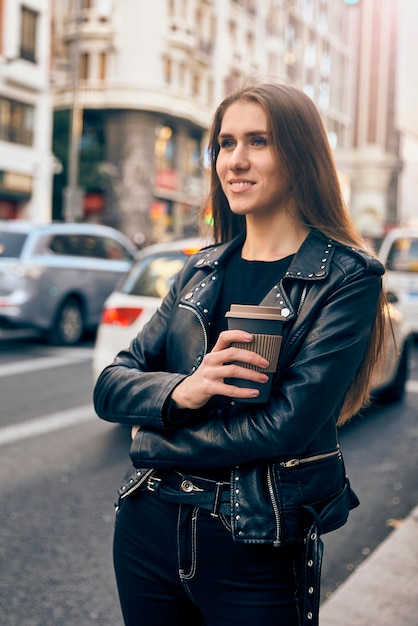 Foto jong blond meisje glimlachend in de straat met een kopje koffie