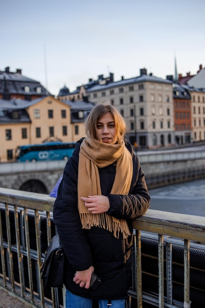 Jong blond meisje in brede koffiesjaal poses in koude winterdag in Stockholm, Zweden