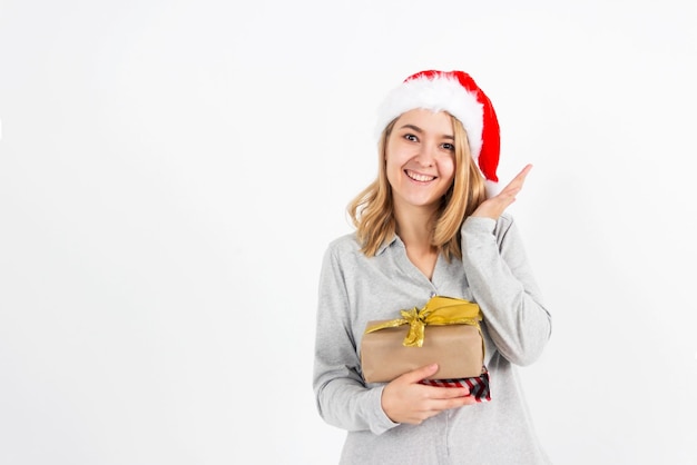 Jong blond meisje in een kerstmuts houdt geschenken in haar hand op een witte achtergrond. Ruimte voor tekst kopiëren