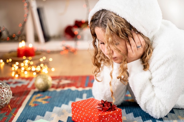 Jong blond meisje met kerstcadeau in kerstsfeer