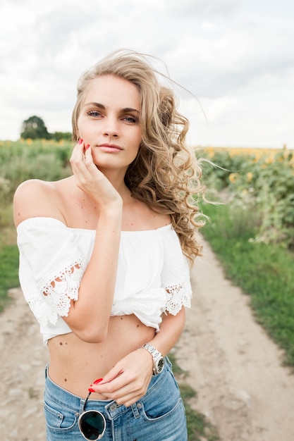 Foto jong blond meisje met lang krullend haar in een veld van zonnebloemen jong blond meisje met lange krullende ha'i