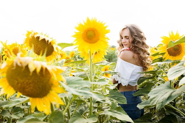Foto jong blond meisje met lang krullend haar in een veld van zonnebloemen