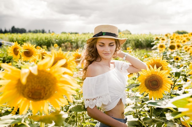 Foto jong blond meisje met lang krullend haar in een veld van zonnebloemen