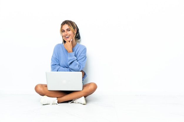 Jong blonde Uruguayaans meisje met laptop die bij het witte muur glimlachen wordt geïsoleerd