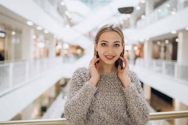 Jong blondie Kaukasisch vrolijk meisje die in modern winkelcentrum glimlachen.