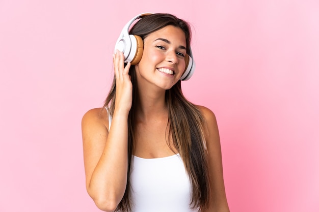 Jong Braziliaans meisje dat op roze het luisteren muziek wordt geïsoleerd