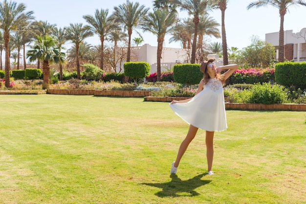 Jong brunette in witte kleding en hoed op een de zomerweide