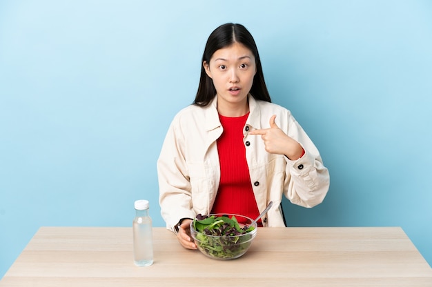 Jong Chinees meisje dat een salade eet die naar zich richt