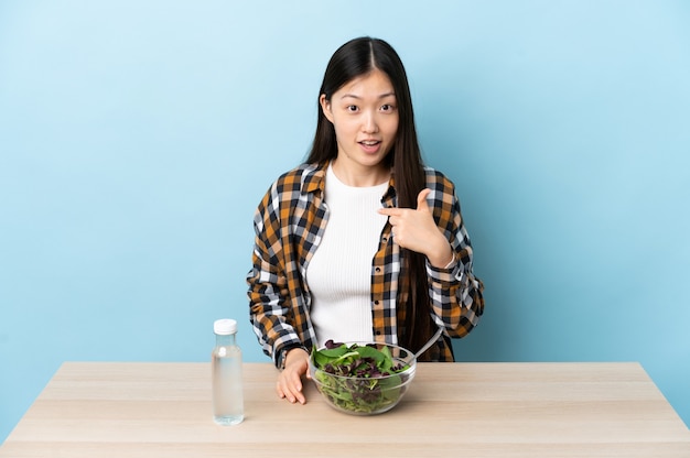 Jong Chinees meisje dat een salade met verrassingsgelaatsuitdrukking eet