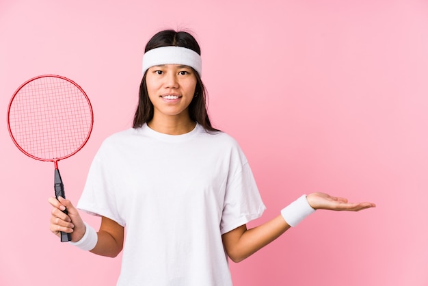 Jong Chinees vrouwen speelbadminton dat iets op een palm toont en een racket in andere houdt