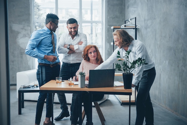 Jong commercieel team dat aan een project met laptop bij lijst en het glimlachen werkt