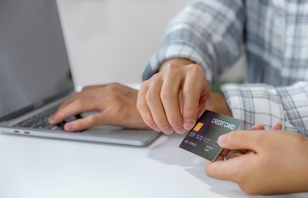 Jong consumentenpaar met een creditcard in de hand, klaar om online te winkelen.