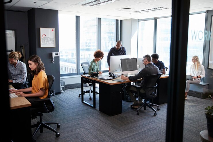 Foto jong creatief team dat samenwerkt op computers in een informeel kantoor gezien vanuit de deuropening