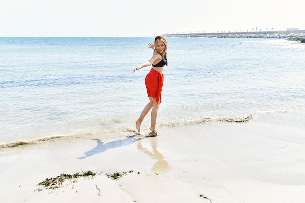 Jong cuacasian meisje glimlachend gelukkig dansen op het strand.