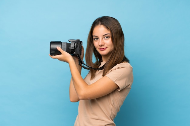 Jong donkerbruin meisje over geïsoleerd blauw met een professionele camera