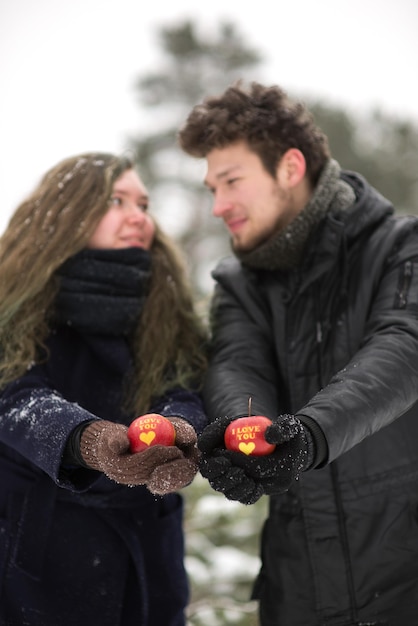 Foto jong echtpaar met appels met tekst terwijl ze in de winter in het bos staan