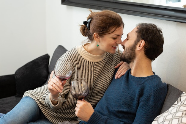 Jong en gelukkig stel dat wijn drinkt en thuis ontspant