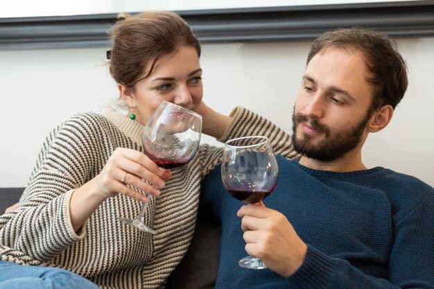 Jong en gelukkig stel dat wijn drinkt en thuis ontspant