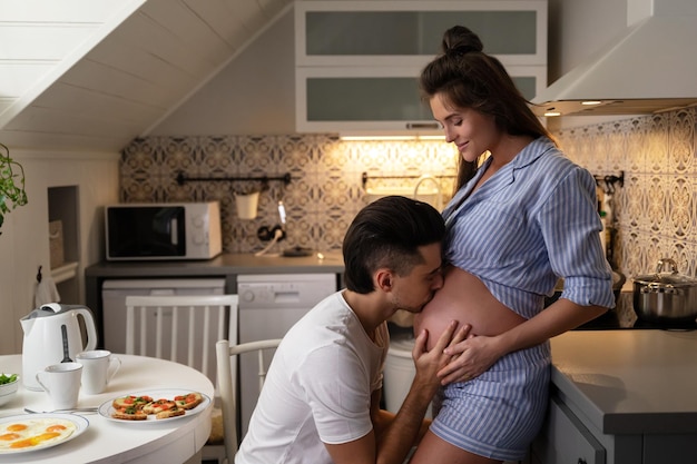 Jong en sensueel stel wacht op een baby Echtgenoot en zijn zwangere vrouw tijdens het ontbijt in een gezellige keuken