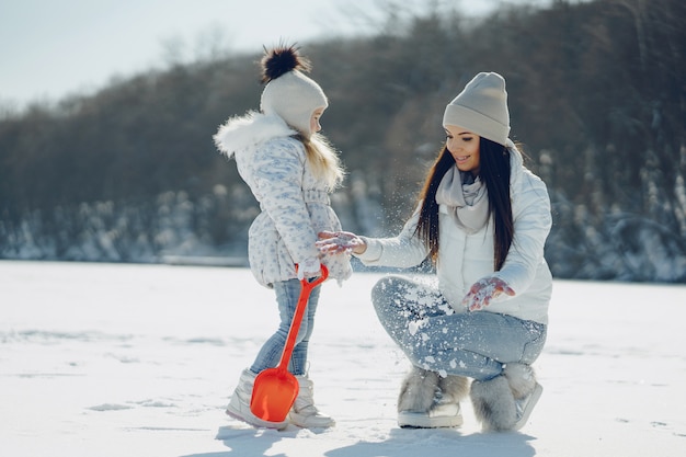 jong en stijlvol moeder spelen met haar kleine schattige dochter in de winter snowpark
