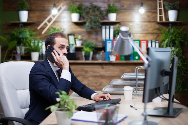 Jong en succesvol bedrijf dat op de computer werkt en een zakelijk gesprek voert via de telefoon. Gesprek over financiën.