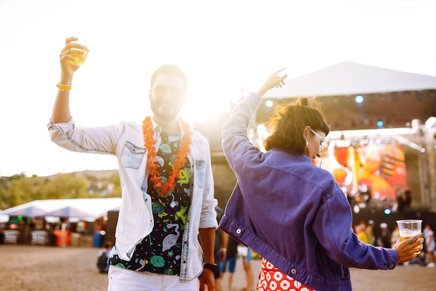 Jong en vrolijk stel op muziekfestival Gelukkige vrienden die bier drinken en plezier hebben