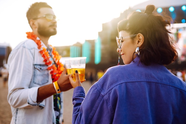 Jong en vrolijk stel op muziekfestival Gelukkige vrienden die bier drinken en plezier hebben