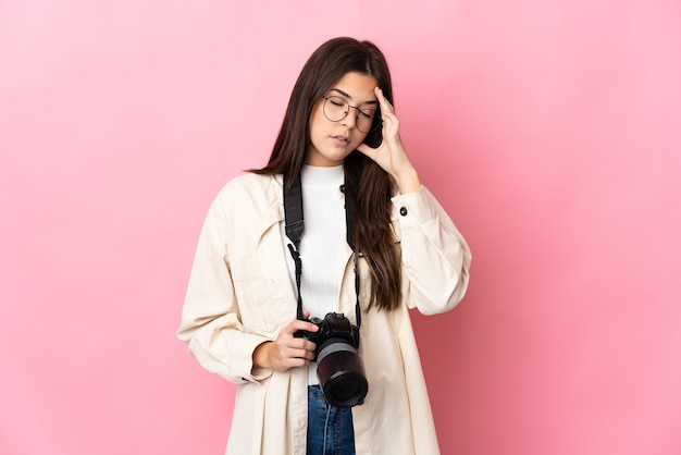 Jong fotograaf Braziliaans meisje dat op roze muur met hoofdpijn wordt geïsoleerd