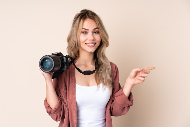 Jong fotograafmeisje over muur die vinger aan de kant richten