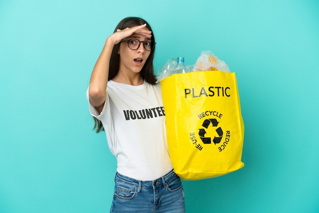 Jong Frans meisje dat een zak vol plastic flessen vasthoudt om te recyclen, doet verrassingsgebaar terwijl ze naar de zijkant kijkt