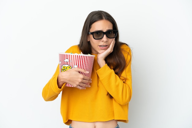 Jong Frans meisje dat op witte achtergrond met 3d glazen wordt geïsoleerd en een grote emmer popcorns houdt